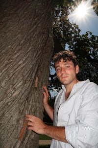 a man leaning against a tree